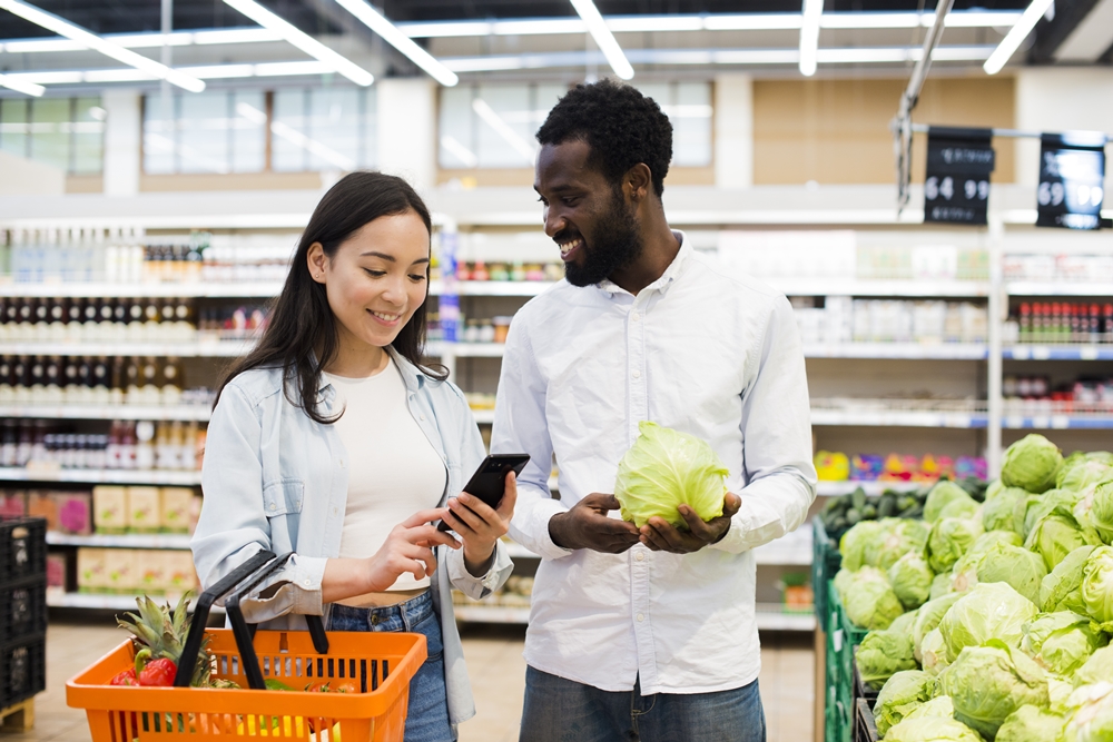casal feliz escolhendo verduras no supermercado